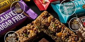 강한 조명 아래 놓인 다양한 설탕 제로 과자와 단백질 바(포장된 것과 포장되지 않은 것)의 근접 사진